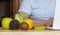 Close-up of healthy fruits and vegetables, with a nutritionist and his computer in the blurred background. Lemon, kiwi, apple,