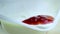 Close-up of healthy red strawberry falling down on white yogurt, concept of healthy food