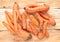 Close-up heap of washed non-standard ugly carrots on  unusual natural wooden background.