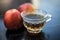 Close up of herbal apple and cinnamon tra on wooden surface in a transparent cup with raw apple.