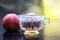 Close up of herbal apple and cinnamon tra on wooden surface in a transparent cup with raw apple.