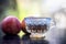 Close up of herbal apple and cinnamon tra on wooden surface in a transparent cup with raw apple.