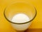 close up and high angle fresh plain homemade yougurt in glass over yellow background. probiotic cold fermented dairy drink