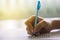 Close up of high school or university student holding a pen writing on answer sheet paper in examination room. College students an