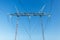 Close-up of a high voltage power line pole isolated against clear blue sky. No visible horizon