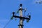 Close-up of high-voltage power lines and power pylons against a blue sky.