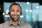 Close up hispanic male worker with video headset smiling and looking at camera, tech support worker working inside