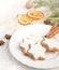 Close up of homemade butter nuts star shaped cookies with icing, pine, orange slices,cinnamon, anise, walnuts and golden ribbon