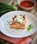Close-up of homemade lasagna with sour cream and fresh chives on wooden background