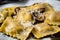 Close-up of homemade mushroom ravioli with truffle oil and grated Parmesan cheese on top
