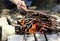 Close-up of a homemade stone grill and a man`s hand throwing firewood. Light a fire on the grill