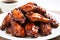 a close-up of honey bbq chicken wings on a white plate