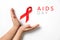 Close up horizontal image of child`s hands holding red ribbon on white background, HIV awareness concept, world AIDS day.