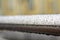 Close-up of horizontal metal wet shiny pipe with big rain water drops on blurred abstract background