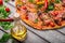 A close-up of hot margarita pizza on a rustic table background. Whole Italian pizza with vegetables and olive oil.