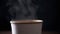 Close up, Hot Steam Rising from a Paper Cup of Hot Coffee on a Black Background