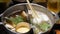 Close up of hotpot shabu with many kind of vegetale while putting meat ball to cooki in boiling hot pot soup. Japanese asian