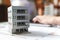 Close up of a house model standing over apartment plans in front of a laptop in a construction bureau