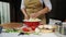 Close-up of housewife, in beige chef apron preparing yeast dough for vegetarian pizza in rustic kitchen o summer cottage