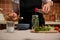 Close-up housewife pouring vinegar into a jar filled with hot chili and fragrant culinary herbs, canning food for winter