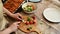 Close-up housewife using kitchen knife cutting onion rings on a wooden chopping board and putting them in a salad bowl