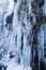 Close up of huge icicles on mountain rock wall beside waterfall