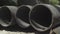 Close-up of huge metal pipes lying under sunlight outdoors. Industrial tubes on factory or plant or manufacturing site.