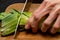 Close up of human hand slicing a fresh green leek