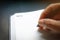 Close up human hands with black pen writing something on blank line notebook with black desk background in dramatic lighting tone.