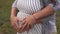 Close-up of human hands holding pregnant belly, happy family awaiting baby.