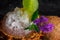 Close-up of ice cocktail in a glass in a pineapple and ice cubes, purple flowers, mint, brown coconut on a dark