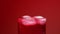 Close up ice cubes spinning in glass of soda water with gas over red background low angle side view slow motion
