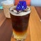 Close-up, iced coffee with ice, decorated with purple pea flowers.