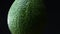 Close-up illustration of central part of green avocado spining counterclockwise on black background.