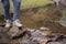 A close-up image of an adventure woman crossing a small nature canal while hiking on the mountain