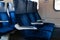 Close up image of blue armchairs in empty train in row of three, no people in wagon, comfortable way of transportation