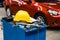 Close-up image of blue metal tool cabinet with safety helmets, glove, document pad on the cabinet with garage background.