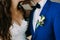 Close-up image of a Boutonniere on the groom`s jacket. Blurred bride and groom are kissing. Artwork