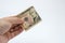 An a close up image of a Caucasian male hand holding a ten Dollar note with a plain background.