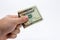 An a close up image of a Caucasian male hand holding a ten Dollar note with a plain background.