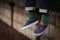 Close up image of dangling feet in blue shoes with vibrant green socks covered in palm trees