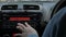 Close up image of driver`s hand press button on car radio, listening music during trip