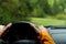 Close up image of Driver`s hands on steering wheel driving a modern off road left hand drive LHD car on the mountain green forest