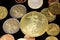 A close up image of Euro coins with a gold American coin on a black background