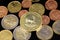 A close up image of Euro coins with a gold South African coin on a black background