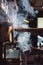 Close-up image of female barista using coffee-making machine to steam milk in cafe