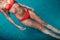 Close-up image of female wearing bikini swimming on back in blue water