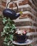 Close up image of flying teapot and tea cup set filled with flowers arrangement on a brick wall