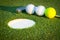 Close up image of golf hole with balls and putt