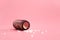 Close-up image of homeopathic globules in glass bottle on pastel pink background. Homeopathy pharmacy, herbal, natural